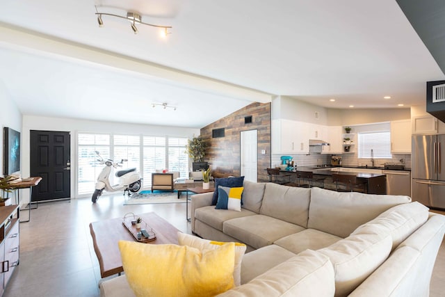 living room featuring sink and vaulted ceiling with beams