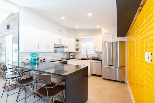 kitchen with a breakfast bar area, kitchen peninsula, stainless steel appliances, decorative backsplash, and white cabinets