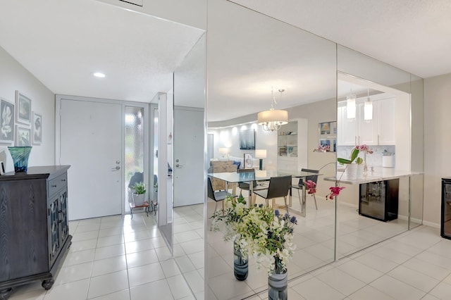 interior space featuring decorative light fixtures, white cabinetry, wine cooler, light tile patterned floors, and kitchen peninsula