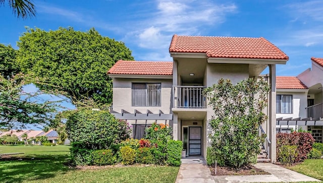 5659 Fairway Park Dr Unit 101, Boynton Beach, FL 33437 - view of front of property with stucco siding, a tile roof, a balcony, and a front yard