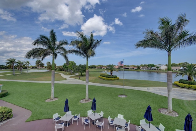 view of community with a water view, a yard, and a patio area