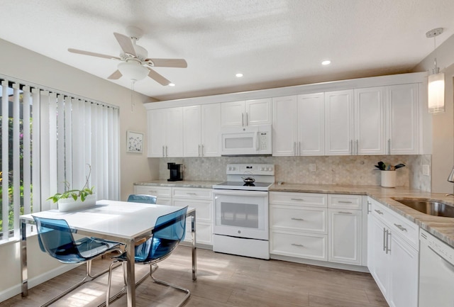 kitchen featuring white cabinetry, sink, decorative backsplash, hanging light fixtures, and white appliances