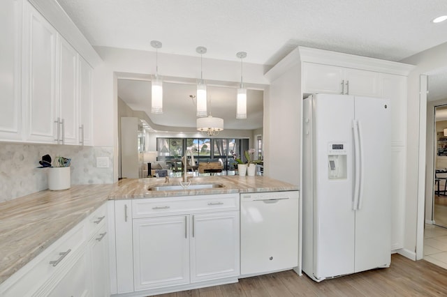 kitchen featuring decorative light fixtures, white cabinetry, sink, light stone countertops, and white appliances