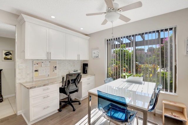 office with light wood-type flooring, built in study area, a ceiling fan, and baseboards