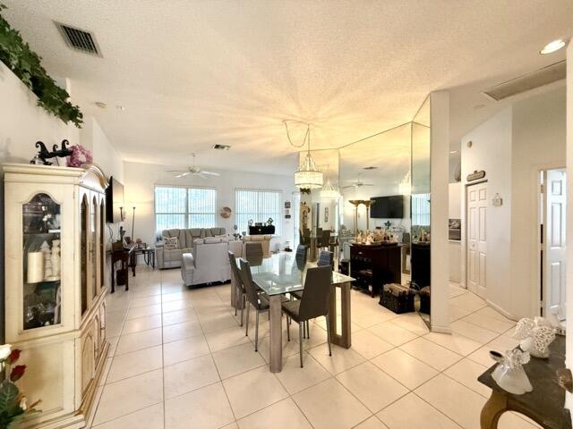 tiled dining space with a textured ceiling and ceiling fan