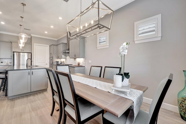 dining space featuring sink, ornamental molding, and light hardwood / wood-style floors