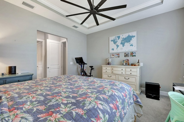 bedroom with ornamental molding, light colored carpet, ceiling fan, and a tray ceiling