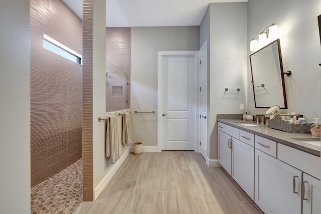 bathroom with a tile shower and vanity