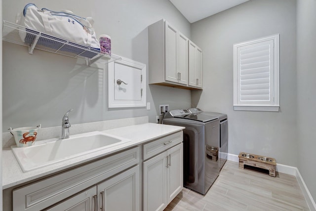 laundry room with cabinets, separate washer and dryer, sink, and light wood-type flooring