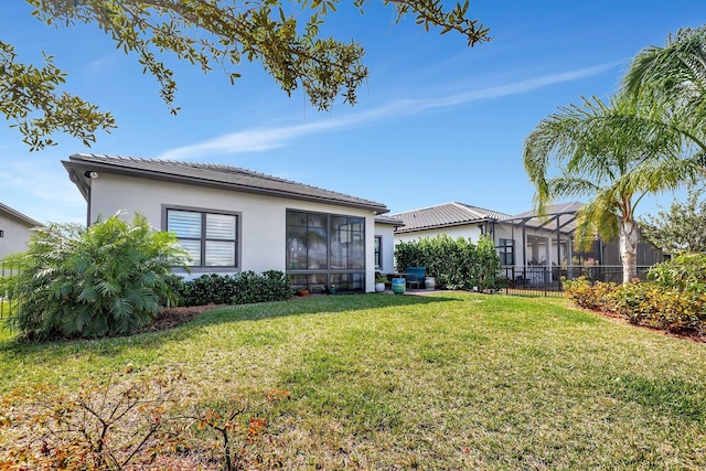 back of property featuring a lanai and a lawn