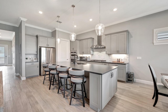 kitchen featuring stainless steel appliances, decorative light fixtures, gray cabinets, and a center island with sink