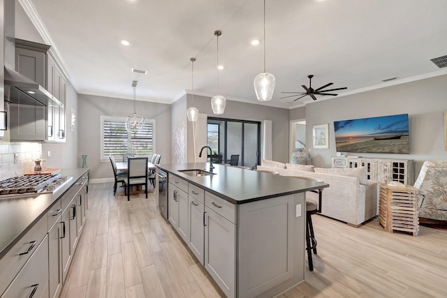 kitchen with pendant lighting, sink, appliances with stainless steel finishes, a kitchen island with sink, and backsplash