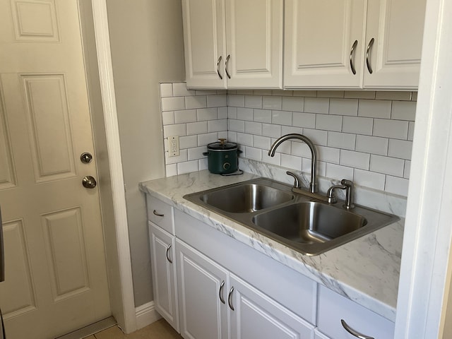 kitchen featuring white cabinetry, sink, and tasteful backsplash