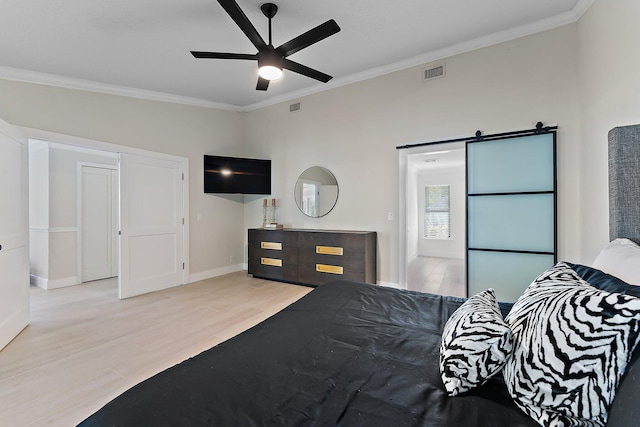 bedroom with crown molding, light hardwood / wood-style floors, and a barn door