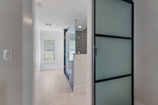 bathroom with ornamental molding, an enclosed shower, and a textured ceiling