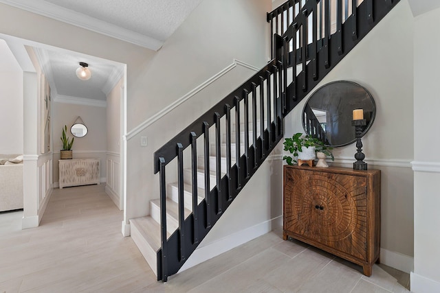 stairs featuring hardwood / wood-style floors, ornamental molding, and a textured ceiling