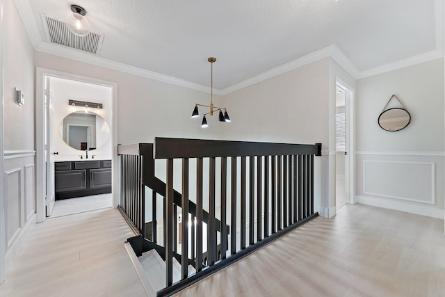 hallway featuring crown molding, sink, and light wood-type flooring