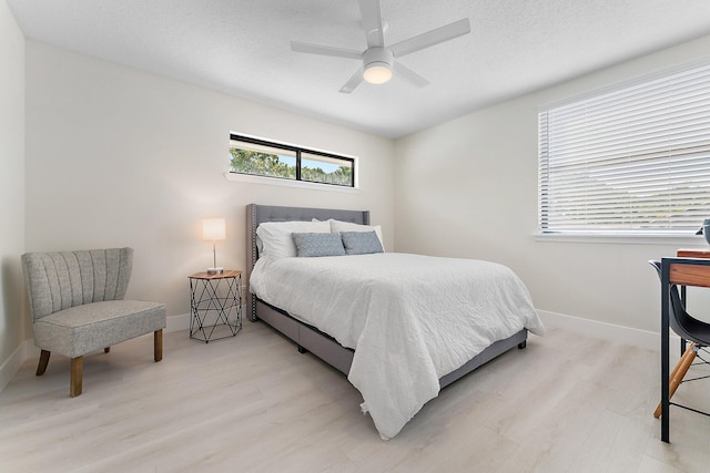 bedroom with ceiling fan, a textured ceiling, and light hardwood / wood-style flooring