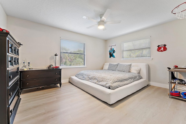 bedroom with ceiling fan, light hardwood / wood-style flooring, and a textured ceiling