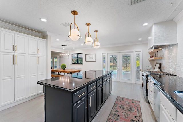 kitchen with french doors, white cabinetry, decorative light fixtures, a center island, and ornamental molding