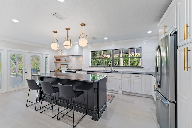 kitchen featuring pendant lighting, white cabinetry, sink, a center island, and stainless steel appliances