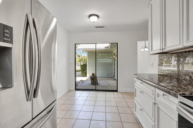 kitchen with tasteful backsplash, white cabinetry, dark stone countertops, light tile patterned floors, and stainless steel refrigerator with ice dispenser