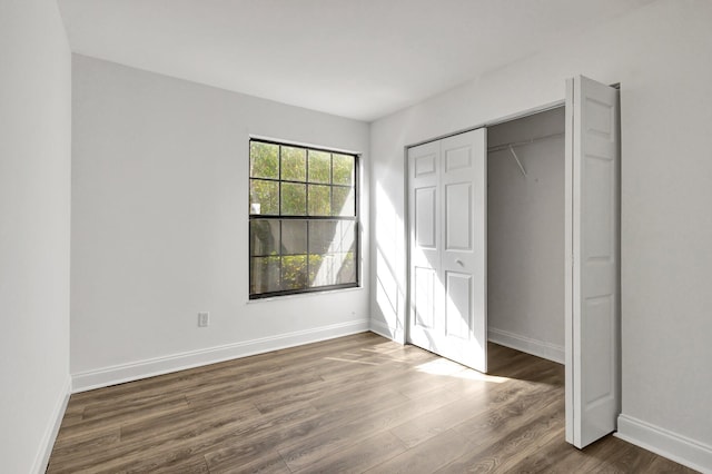 unfurnished bedroom with dark hardwood / wood-style flooring and a closet