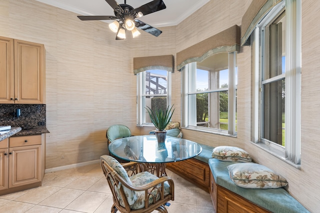 dining area with light tile patterned floors, ornamental molding, a ceiling fan, and baseboards