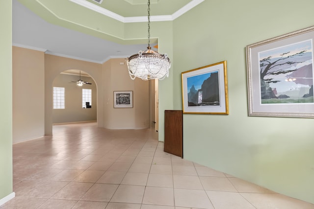 empty room with ceiling fan with notable chandelier, arched walkways, crown molding, and light tile patterned floors