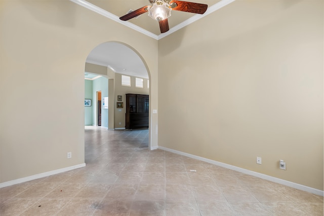 empty room featuring ornamental molding, arched walkways, and baseboards