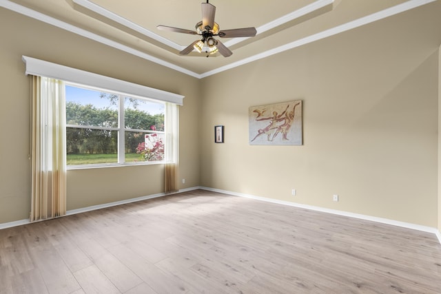 spare room with crown molding, baseboards, a raised ceiling, and wood finished floors