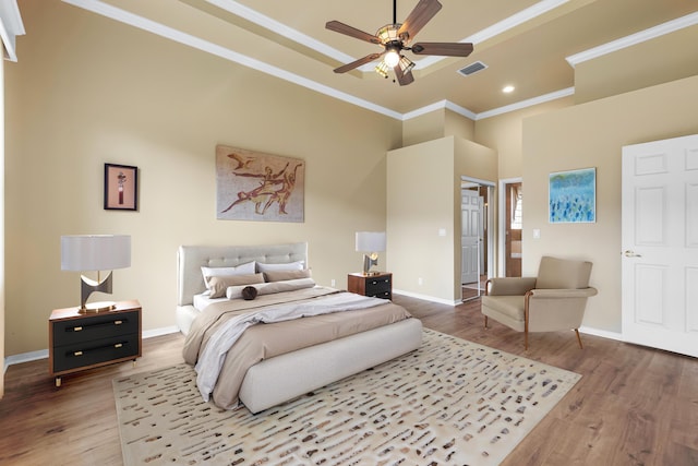 bedroom featuring visible vents, crown molding, baseboards, and wood finished floors