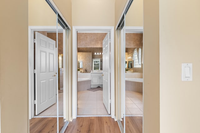 hallway featuring light tile patterned floors, a sink, and a wealth of natural light