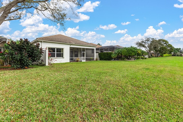 back of property featuring a lawn, a tile roof, and a sunroom