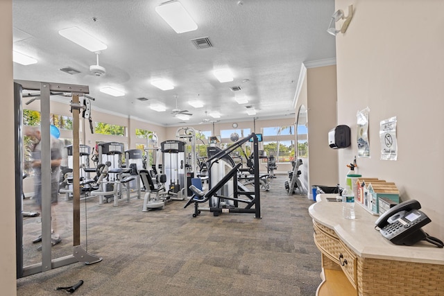 workout area with ceiling fan, a textured ceiling, visible vents, and crown molding