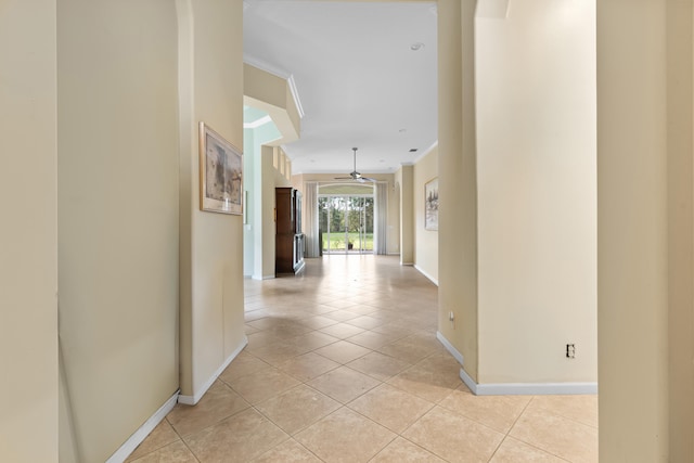 hall with baseboards, crown molding, and light tile patterned flooring