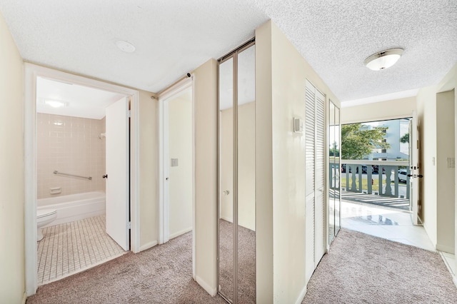 corridor featuring light colored carpet and a textured ceiling