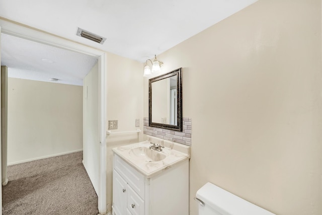 bathroom featuring vanity, tasteful backsplash, and toilet