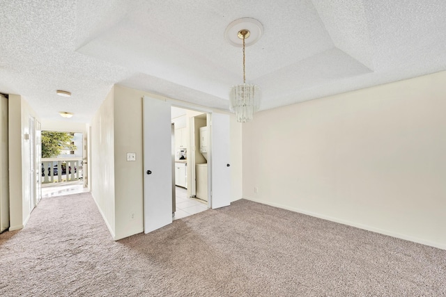 carpeted spare room featuring a notable chandelier and a textured ceiling