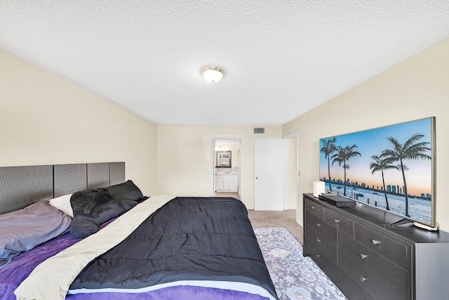 carpeted bedroom with connected bathroom and a textured ceiling