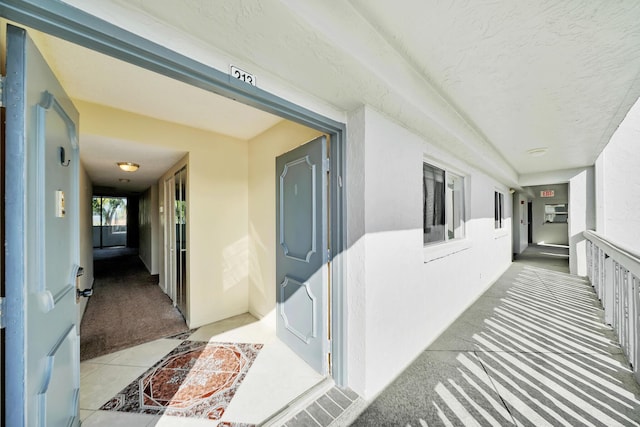 hall with carpet flooring and a textured ceiling