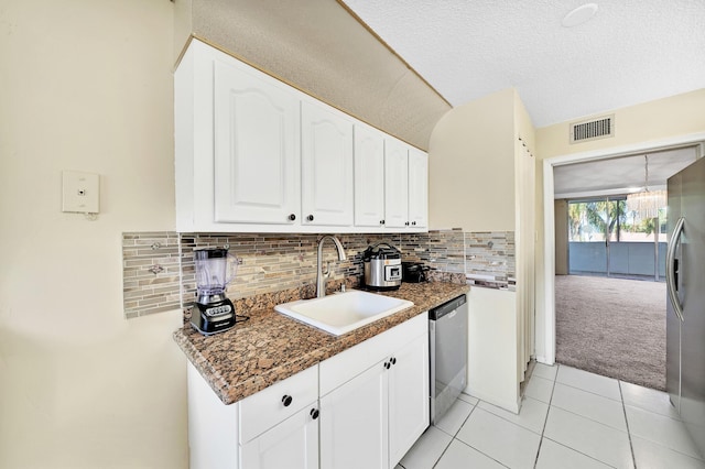 kitchen with appliances with stainless steel finishes, white cabinetry, sink, dark stone countertops, and decorative backsplash