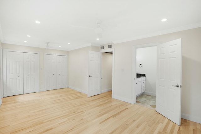 unfurnished bedroom with ensuite bathroom, crown molding, light hardwood / wood-style flooring, multiple closets, and ceiling fan