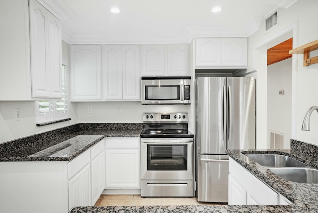 kitchen featuring dark stone countertops, stainless steel appliances, and white cabinets