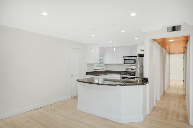 kitchen with stainless steel appliances, dark stone countertops, white cabinets, and light hardwood / wood-style floors