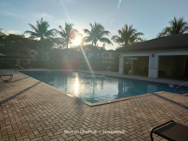 pool at dusk featuring a patio area