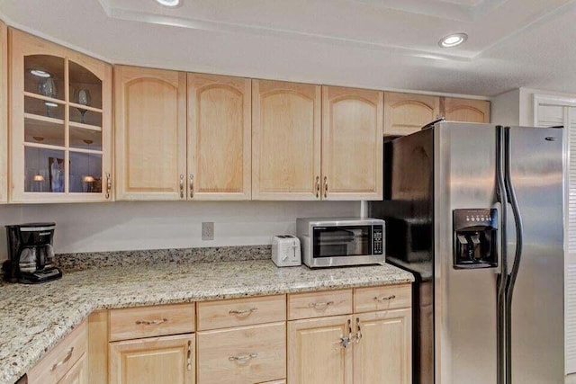 kitchen featuring light stone counters, stainless steel appliances, and light brown cabinetry