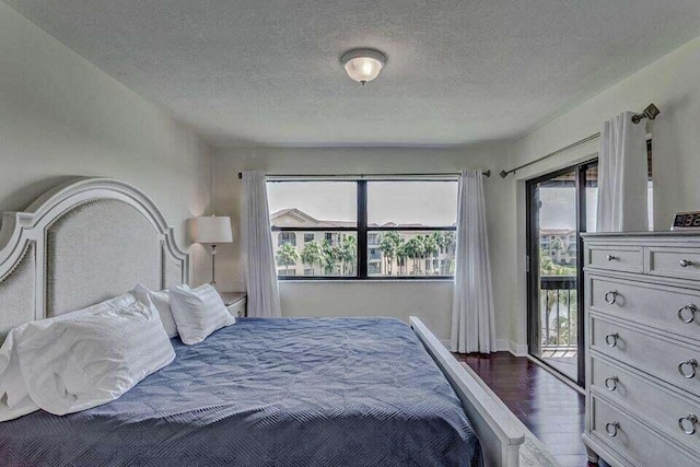 bedroom featuring dark wood-type flooring, a textured ceiling, and access to outside