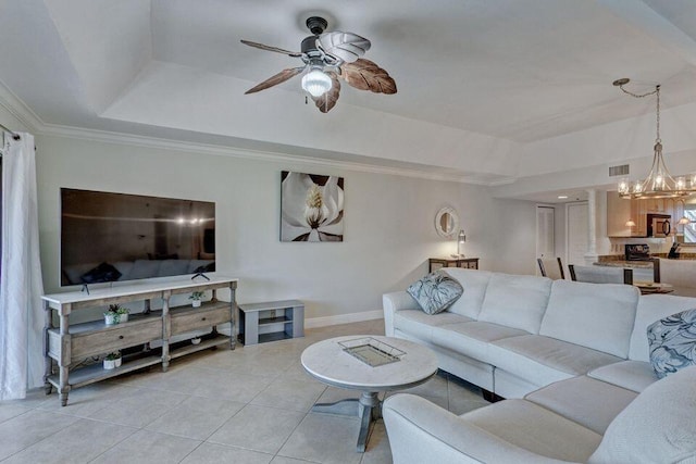 living room with a raised ceiling, light tile patterned flooring, ornamental molding, and ceiling fan with notable chandelier