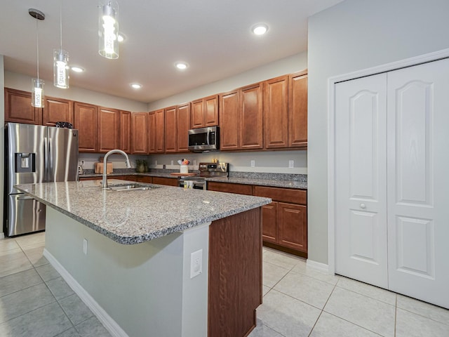 kitchen featuring sink, hanging light fixtures, stainless steel appliances, an island with sink, and light tile patterned flooring